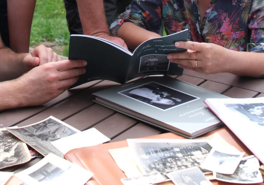 Livre de famille Bavardises ouvert sur une table avec des photos de famille.